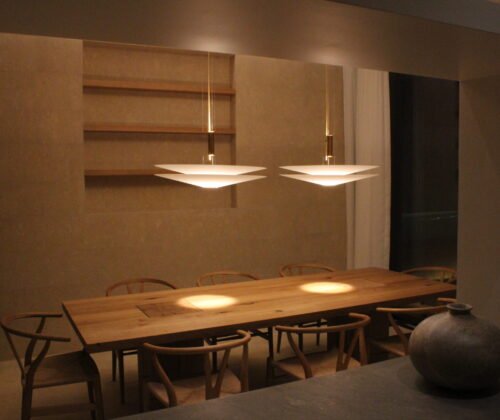 Warm ambient dining area with wooden table and designer pendant lights at AM Villa
