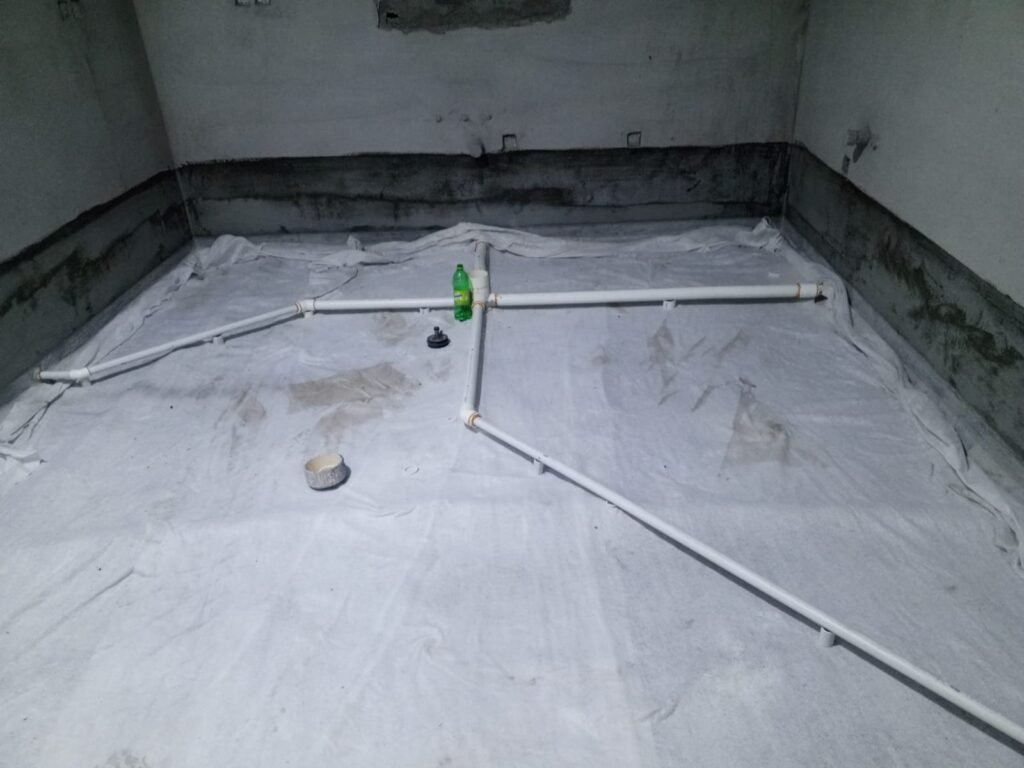 Wet-area floor waterproofed and turned up the walls, with the drain pipes laid on it