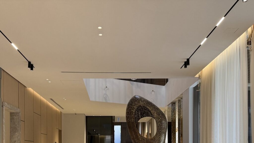Finished gypsum ceiling with track and recessed lighting, a linear air-conditioning diffuser and access panels