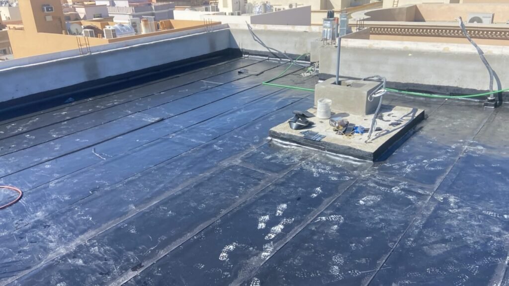 Bitumen membrane on a villa roof, laid in overlapping strips and turned up at the parapet